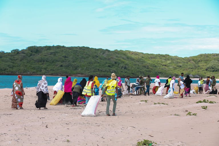 A diverse group participates in a community beach cleanup in Lamu, Kenya.
